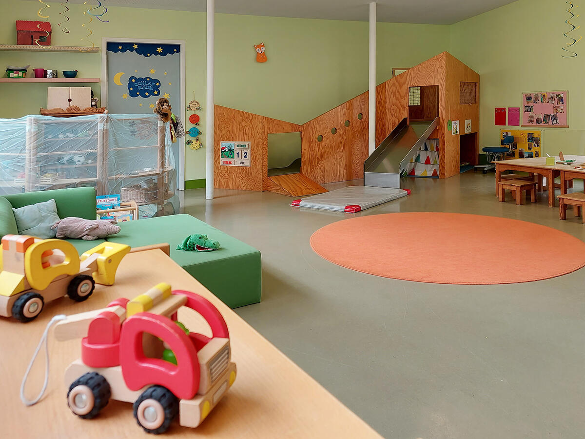 Zimmer der Kita Pfaffenwald mit Spielzeug, Spielturm, Couch und Tisch