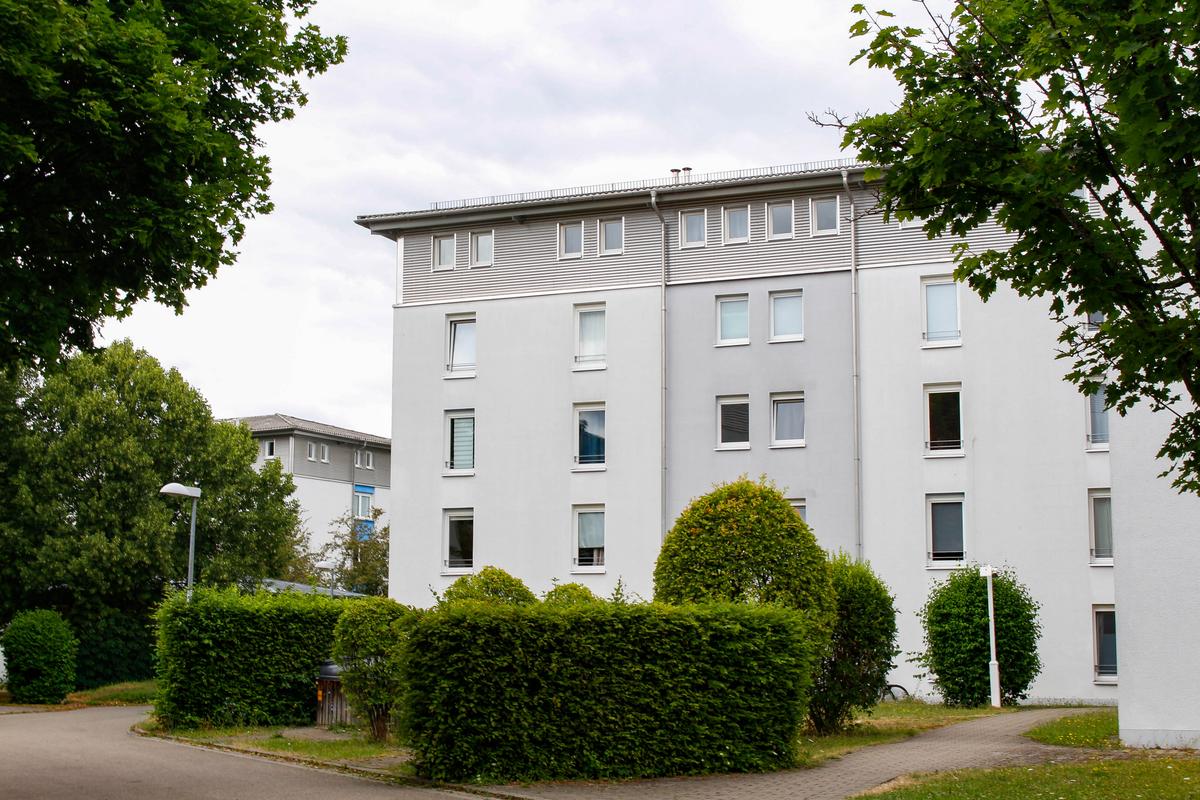 White building of the Ludwigsburg student village. Hedges and trees can be seen in front of it.