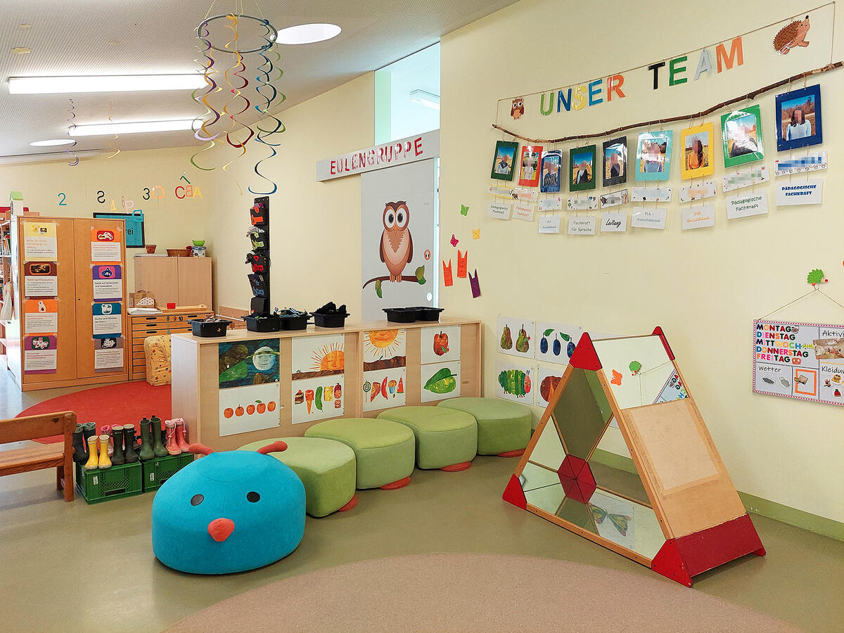 Gruppenvorraum der Kita Pfaffenwald mit Girlanden, Schränken und einer Sitzgelegenheit in Form einer Raupe