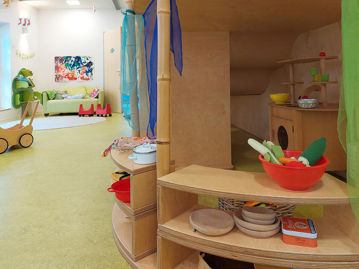 Spielküche und Leseecke mit Couch im Gruppenraum der Kita Villa MiO