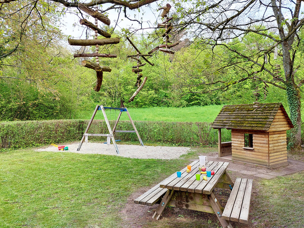 Garten der Kita Löwenzahn mit Bank, Häuschen und Schaukel