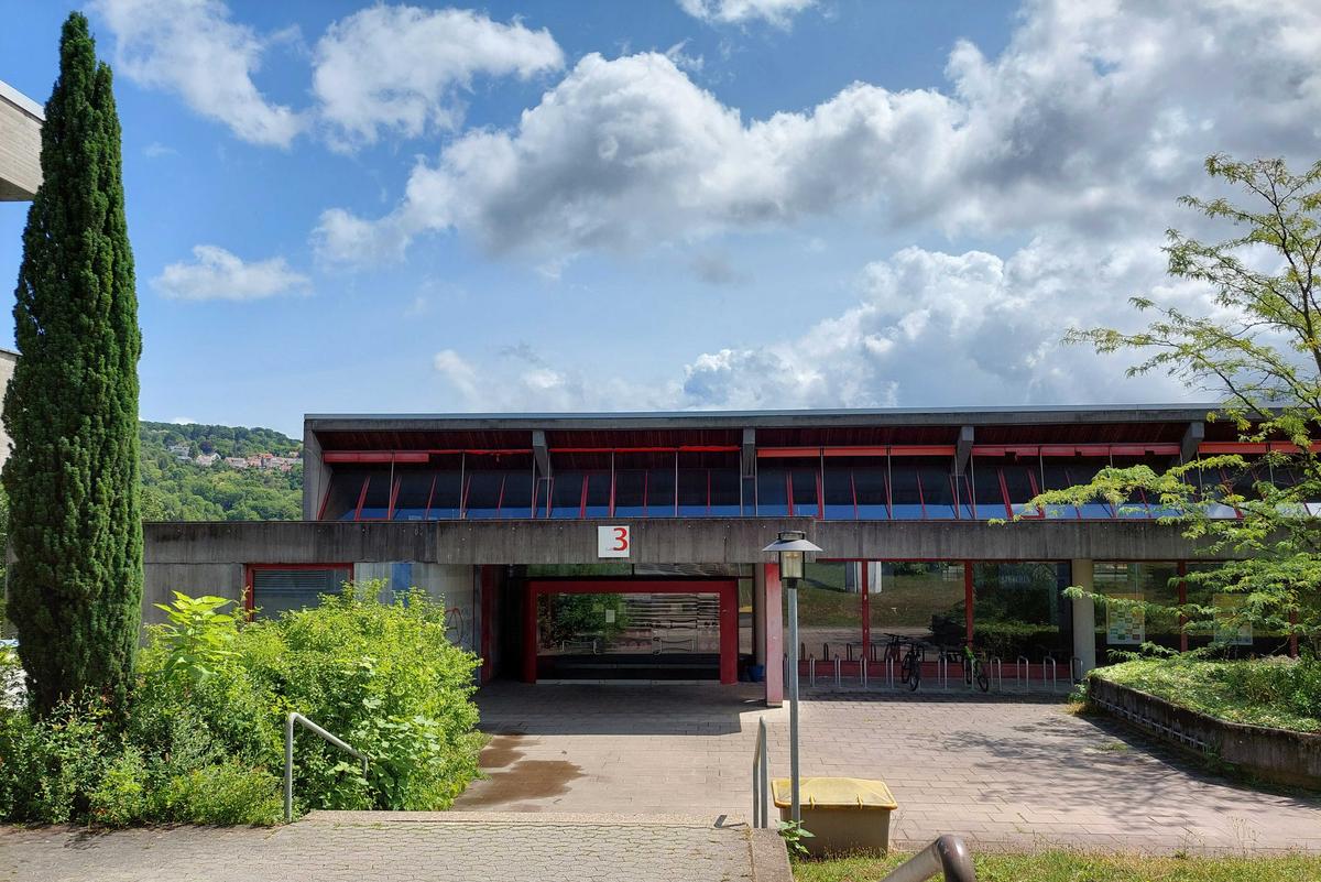 Exterior view of the Flandernstrasse canteen. Low-rise building with large entrance area. Trees and shrubs to the left and right