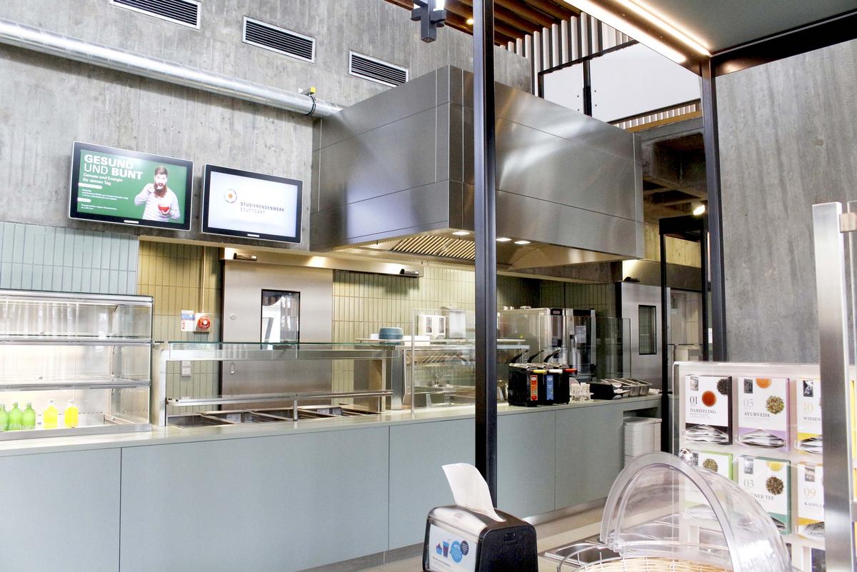 Food counter in the Kunstakademie canteen. In the foreground you can see a tea bar and napkins. Two screens hang above the food counter.