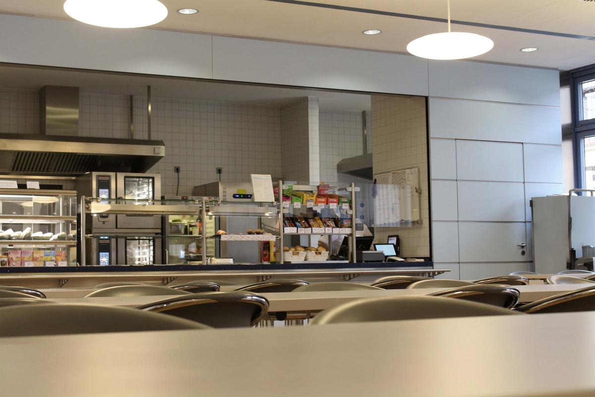 Essensausgabe der Mensa Horb. Im Vordergrund stehen Tische und Stühle